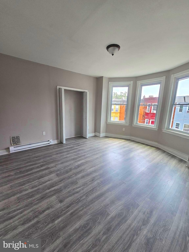 spare room with dark hardwood / wood-style floors and baseboard heating