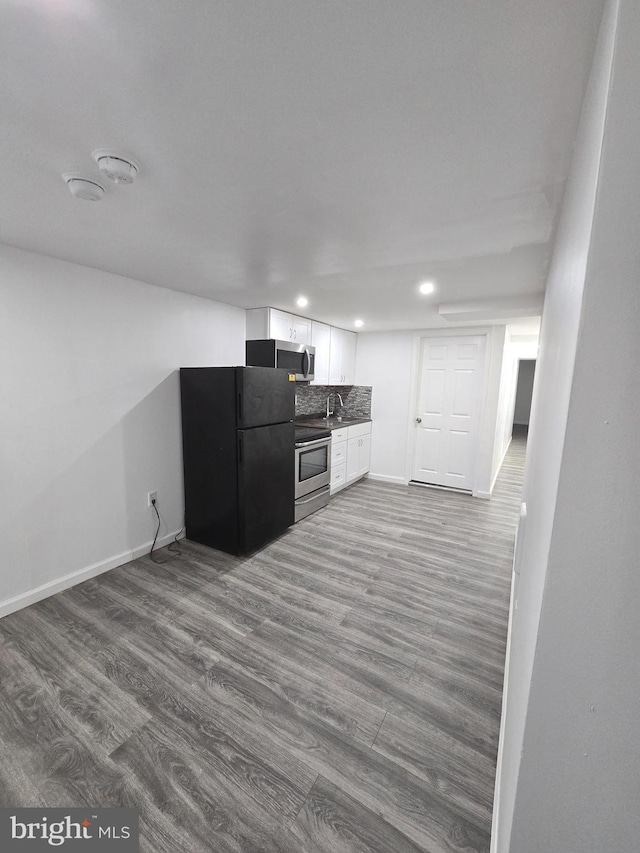 kitchen featuring decorative backsplash, appliances with stainless steel finishes, hardwood / wood-style floors, and white cabinets