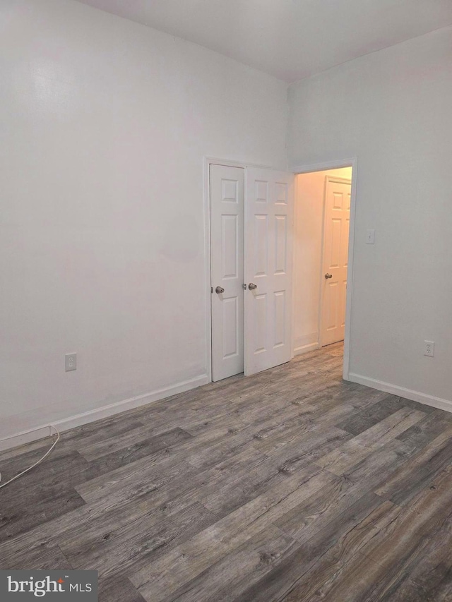 unfurnished room featuring baseboards and dark wood-style floors