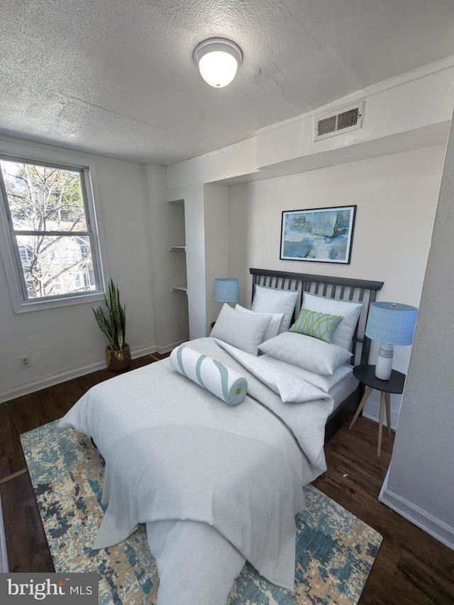 bedroom with a textured ceiling and dark hardwood / wood-style flooring