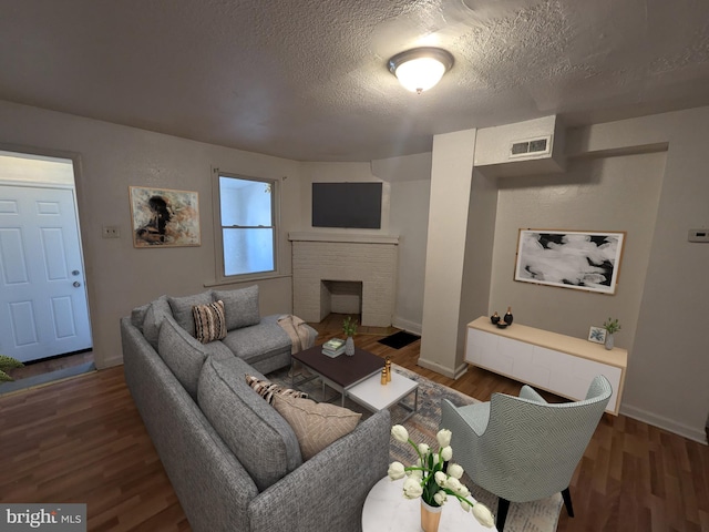 living room featuring dark hardwood / wood-style flooring, a textured ceiling, and a fireplace