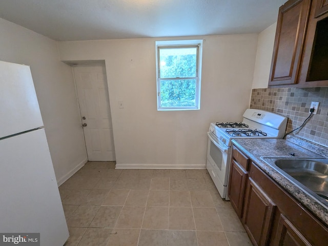 kitchen with light tile patterned flooring, white appliances, and decorative backsplash