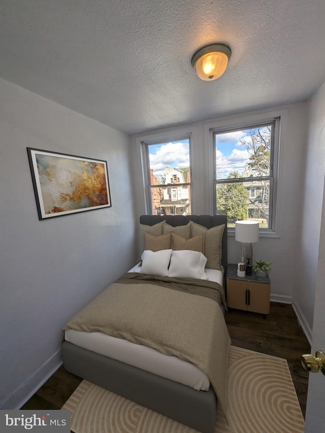 bedroom featuring dark hardwood / wood-style flooring and a textured ceiling