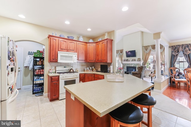 1420 N Red Maple Way, Downingtown, PA 19335 - kitchen with white appliances, a sink, light tile patterned floors, a kitchen breakfast bar, and a glass covered fireplace