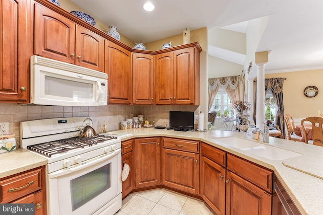 kitchen featuring backsplash, light tile patterned floors, ornate columns, sink, and white appliances