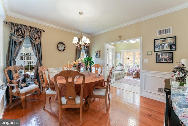 dining space featuring light hardwood / wood-style floors, an inviting chandelier, and ornamental molding