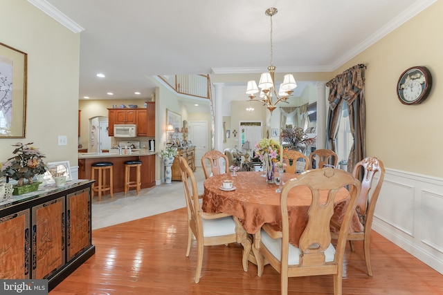 dining area featuring a chandelier, light wood-type flooring, and crown molding