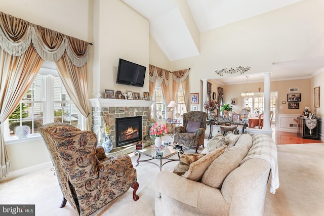 living room featuring light carpet, a notable chandelier, ornate columns, and a fireplace