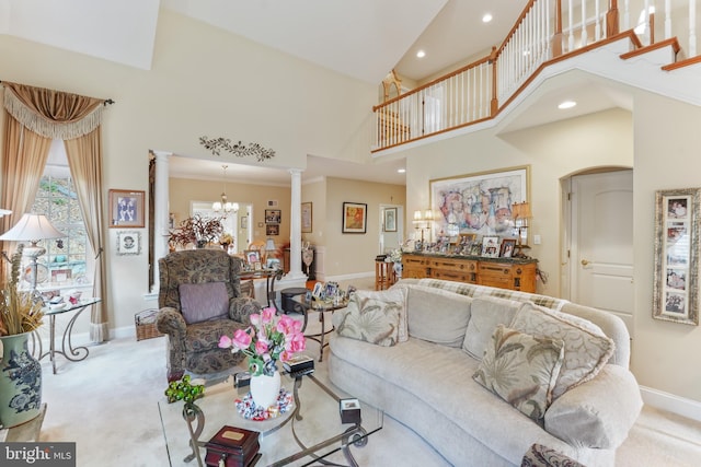 carpeted living room featuring ornate columns, high vaulted ceiling, and an inviting chandelier