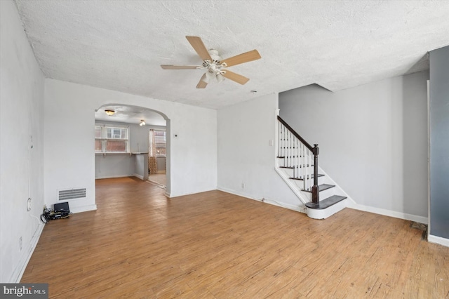 unfurnished living room with light wood-type flooring, a textured ceiling, and ceiling fan