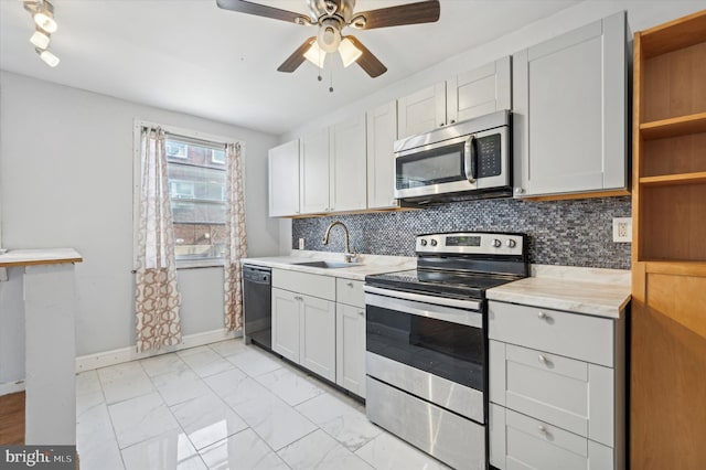 kitchen with stainless steel appliances, white cabinets, decorative backsplash, sink, and ceiling fan