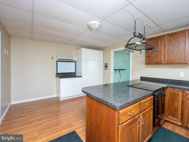 kitchen with a wall unit AC, a paneled ceiling, electric range, light hardwood / wood-style flooring, and decorative light fixtures