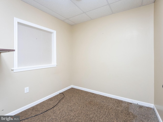 empty room featuring a paneled ceiling and carpet floors