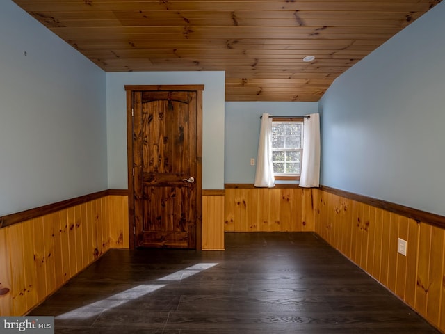 spare room with wood walls, lofted ceiling, wooden ceiling, and dark hardwood / wood-style floors