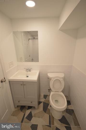 bathroom with tile patterned floors, vanity, toilet, and tile walls