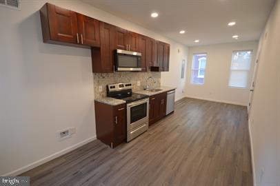 kitchen with dark hardwood / wood-style flooring, sink, appliances with stainless steel finishes, and decorative backsplash