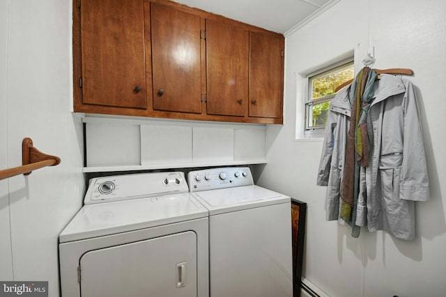 clothes washing area with washer and dryer, a baseboard radiator, and cabinets