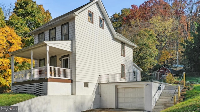 view of property exterior featuring a storage shed, covered porch, and a garage