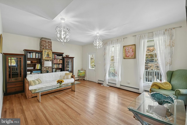 living room with a chandelier, light hardwood / wood-style floors, and a baseboard heating unit