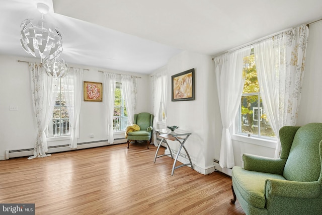 living area with a wealth of natural light, light hardwood / wood-style floors, and a notable chandelier