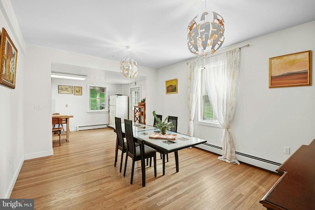 dining area with light wood-type flooring, baseboard heating, and a notable chandelier