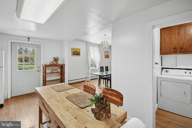 dining space featuring a baseboard heating unit, washer / clothes dryer, an inviting chandelier, and light hardwood / wood-style floors