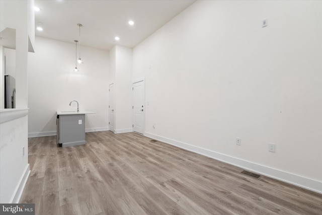 interior space featuring a towering ceiling, sink, and light hardwood / wood-style flooring