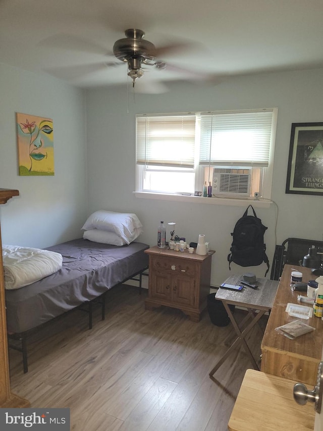 bedroom featuring cooling unit, hardwood / wood-style flooring, and ceiling fan