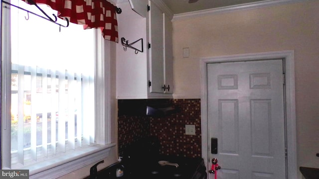 interior space featuring tasteful backsplash, ornamental molding, and white cabinets