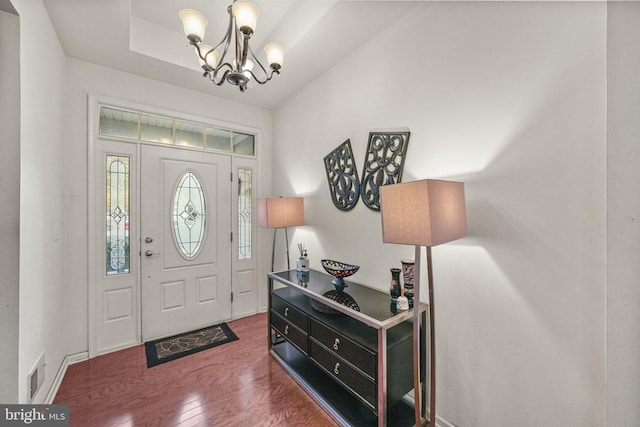 foyer featuring hardwood / wood-style floors, a notable chandelier, and a raised ceiling