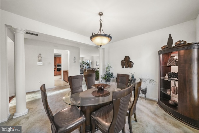 dining room featuring ornate columns and light colored carpet