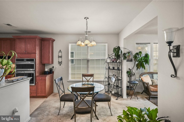 dining space featuring light carpet and an inviting chandelier