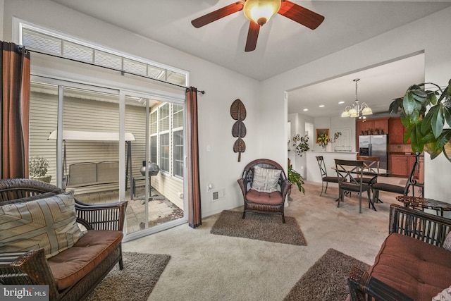 carpeted living room featuring ceiling fan with notable chandelier