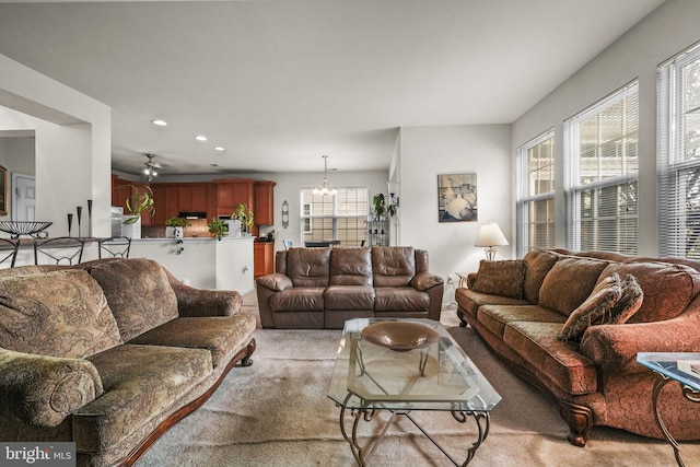 carpeted living room featuring ceiling fan with notable chandelier