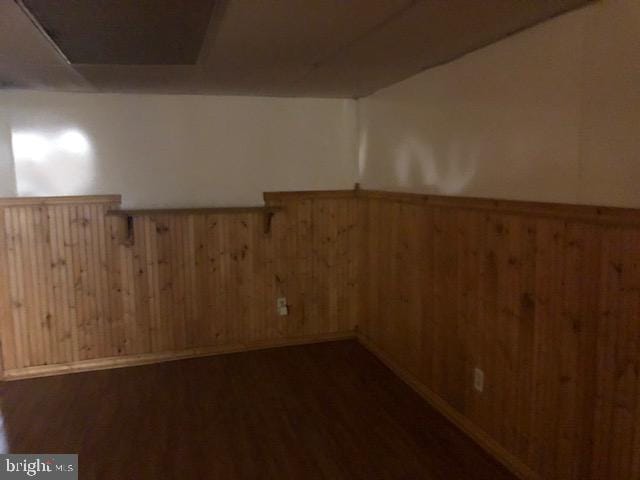 basement featuring dark hardwood / wood-style floors and wood walls