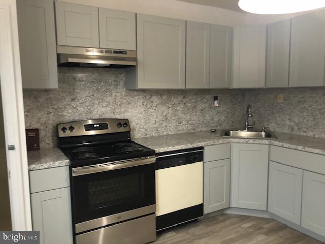 kitchen with electric range, dishwasher, sink, decorative backsplash, and light wood-type flooring