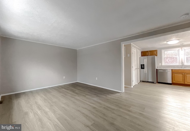 unfurnished living room featuring a textured ceiling, light hardwood / wood-style floors, crown molding, and sink