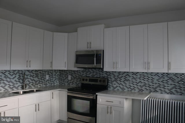 kitchen with white cabinets, appliances with stainless steel finishes, and radiator