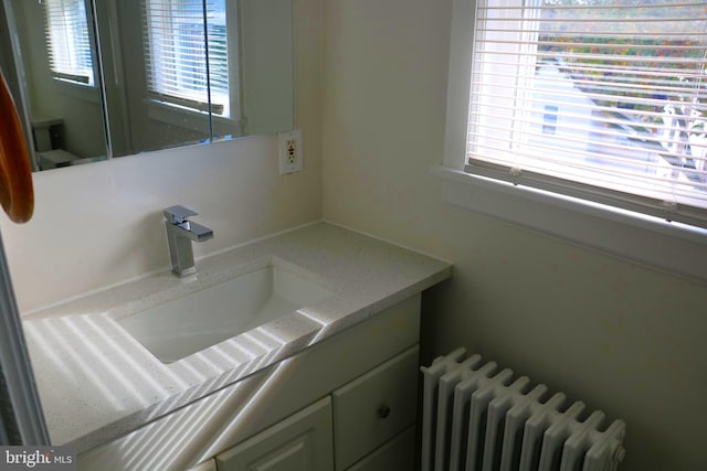 bathroom featuring a wealth of natural light, radiator heating unit, and vanity