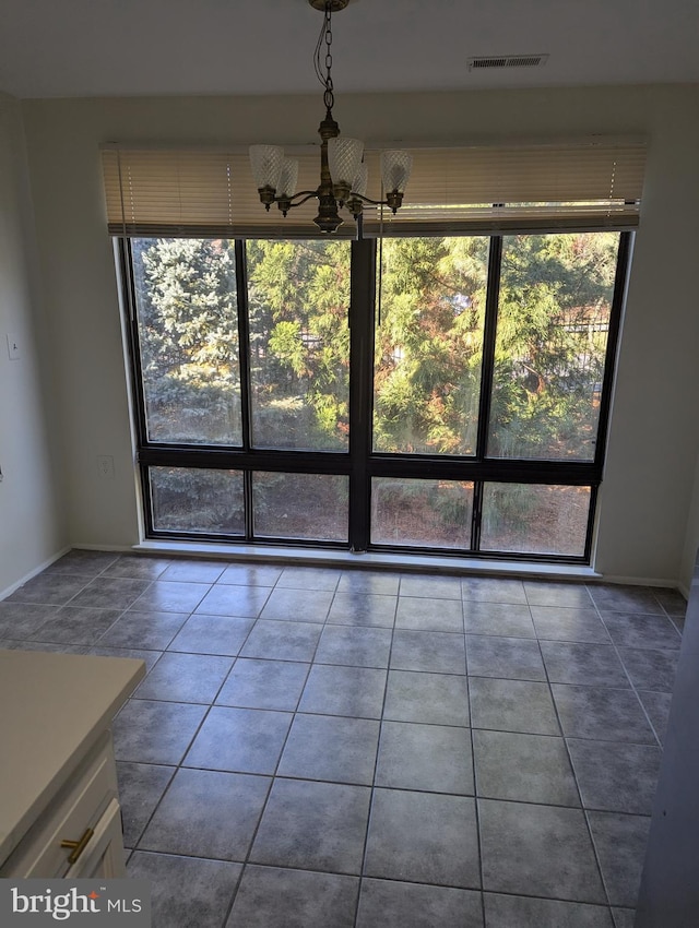 unfurnished dining area with a chandelier, tile patterned floors, and a healthy amount of sunlight