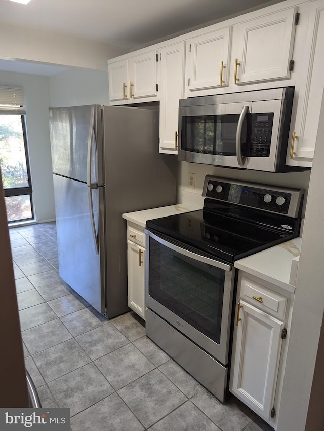 kitchen featuring stainless steel appliances, white cabinetry, and light tile patterned floors