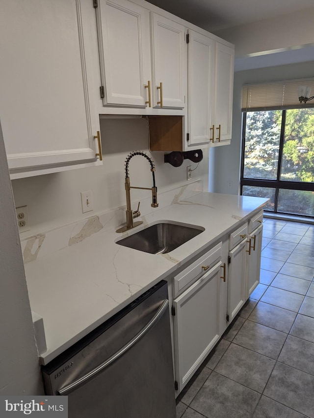 kitchen featuring sink, dark tile patterned flooring, light stone countertops, white cabinets, and dishwasher