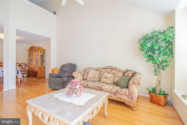 living room with a towering ceiling, hardwood / wood-style flooring, and ceiling fan