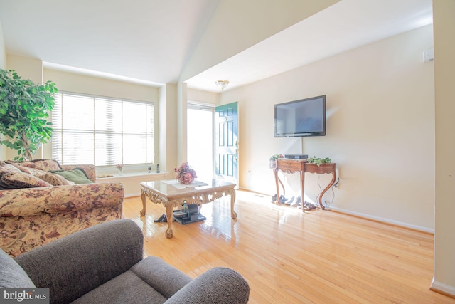 living room with light hardwood / wood-style floors and vaulted ceiling