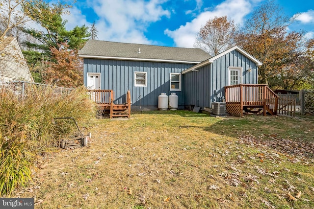 back of property with central AC unit and a lawn