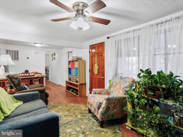 living room with ceiling fan, hardwood / wood-style floors, and a textured ceiling