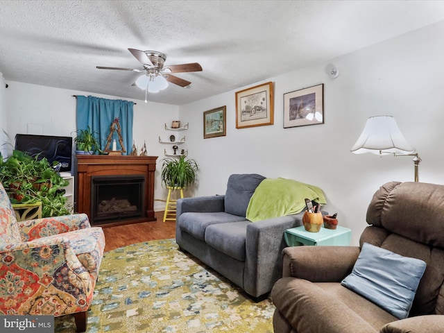 living room featuring ceiling fan, wood-type flooring, and a textured ceiling