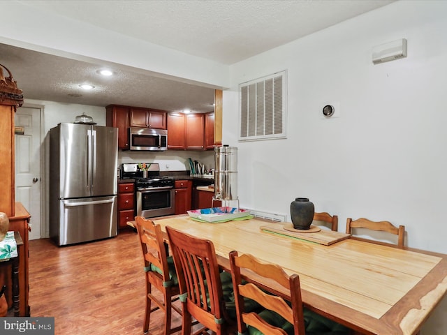 kitchen featuring a textured ceiling, stainless steel appliances, and light hardwood / wood-style flooring