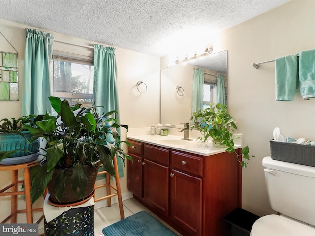 bathroom featuring tile patterned floors, a healthy amount of sunlight, a textured ceiling, and toilet