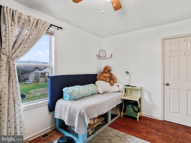 bedroom featuring ceiling fan, dark wood-type flooring, and a textured ceiling